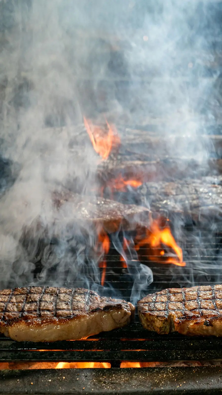 Bifes en la parrilla con llamas y humo