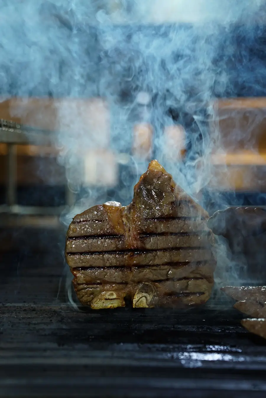 Un corte grueso sobre la parrilla, entre el humo