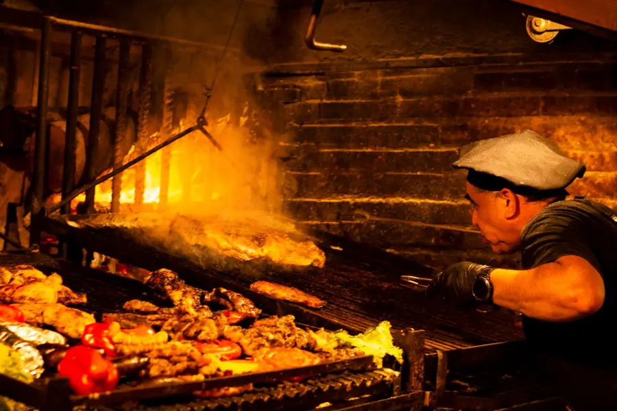 El parrillero acomodando la brasa debajo de la parrilla