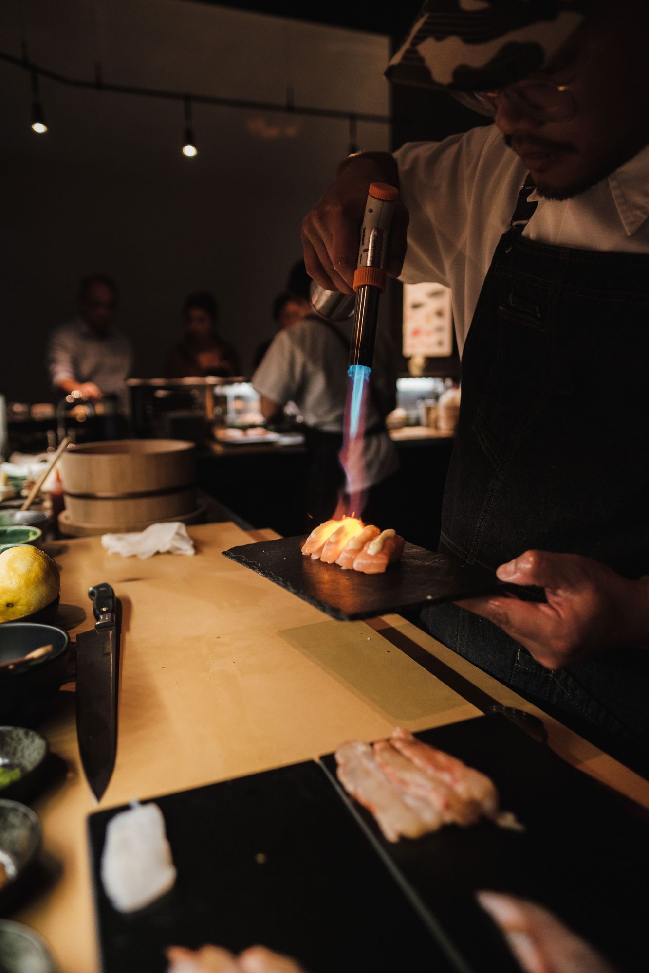 Itamae de Kumo flambeando nigiris de salmón en la barra