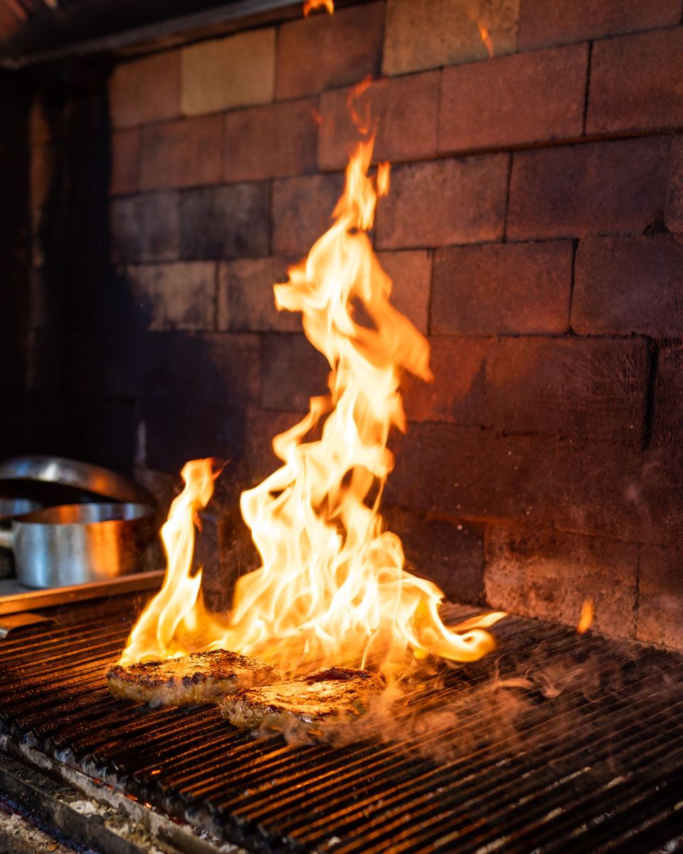 Cortes de carne sobre una parrilla con llamas altas