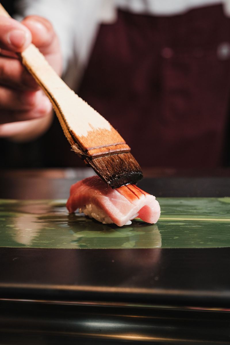 El itamae pincela un nigiri con nikiri