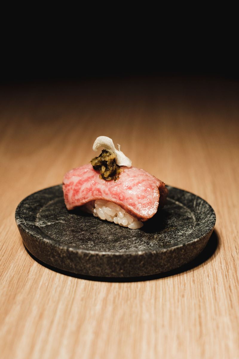 Nigiri de wagyu sobre una piedra volcánica, con luz cálida de barra